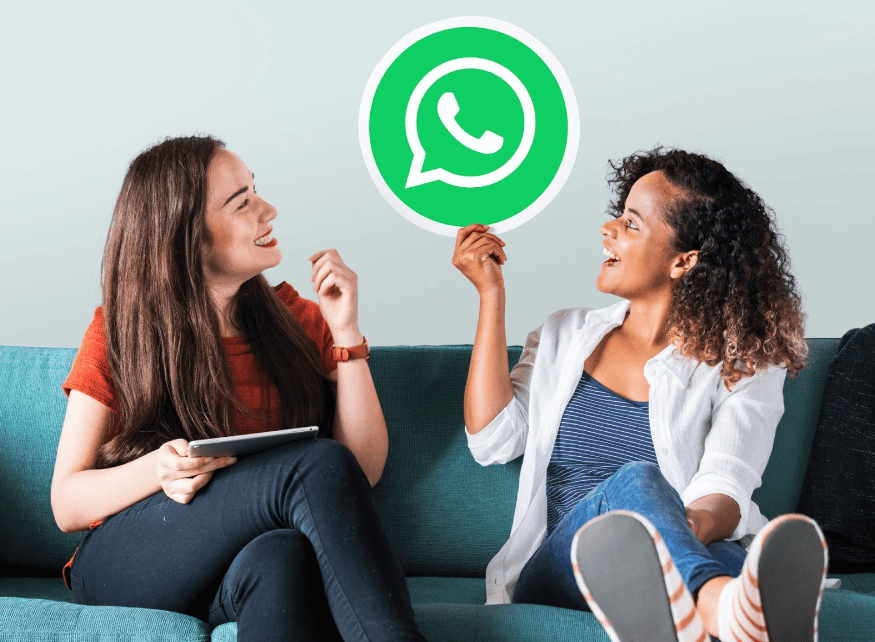 A imagem mostra duas mulheres sentadas em um sofá. A mulher à esquerda está segurando um tablet e sorrindo, enquanto a mulher à direita está gesticulando com a mão e também sorrindo. Acima delas, há um grande ícone do WhatsApp, que é um balão de fala verde com um telefone branco dentro. O fundo é claro, destacando a interação animada entre as duas mulheres, que parecem estar conversando sobre algo divertido ou interessante.
A imagem simboliza uma profissional e uma cliente satisfeitas pelo bom uso de estratégias de vendas pelo whatsapp.