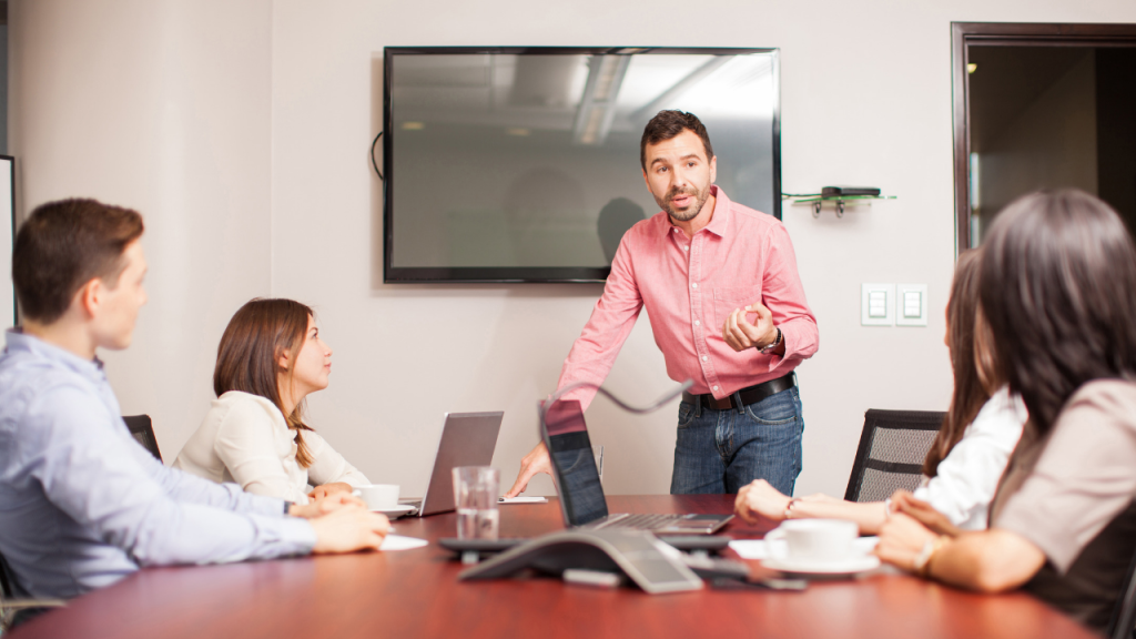 Reunião de marketing numa sala iluminada com computadores à mesa